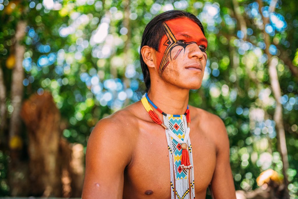 indian from the pataxó tribe smiling. brazilian indian from southern bahia with necklace and traditional facial paintings looking to the right